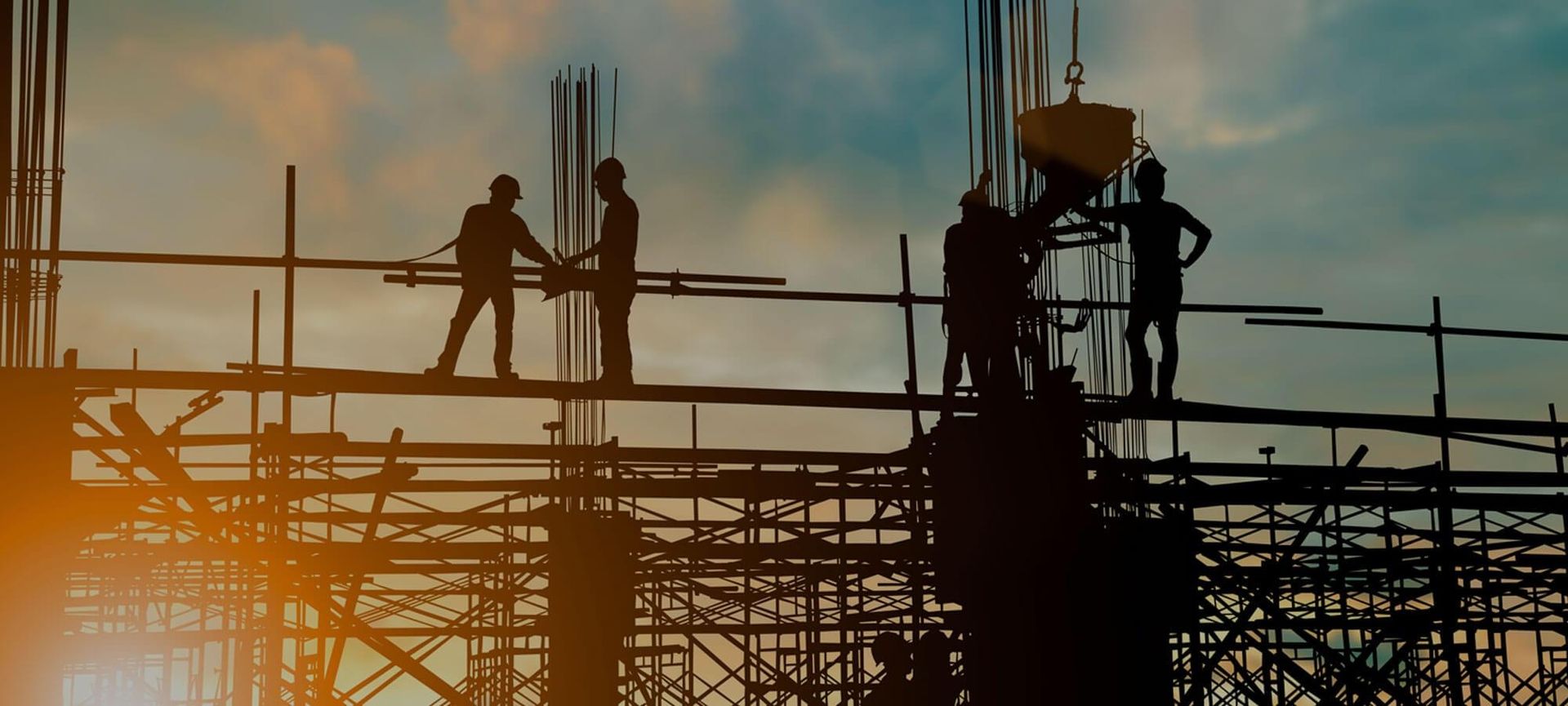 Bauarbeiter arbeiten beim Sonnenaufgang auf einem Gerüst eines Gebäudes